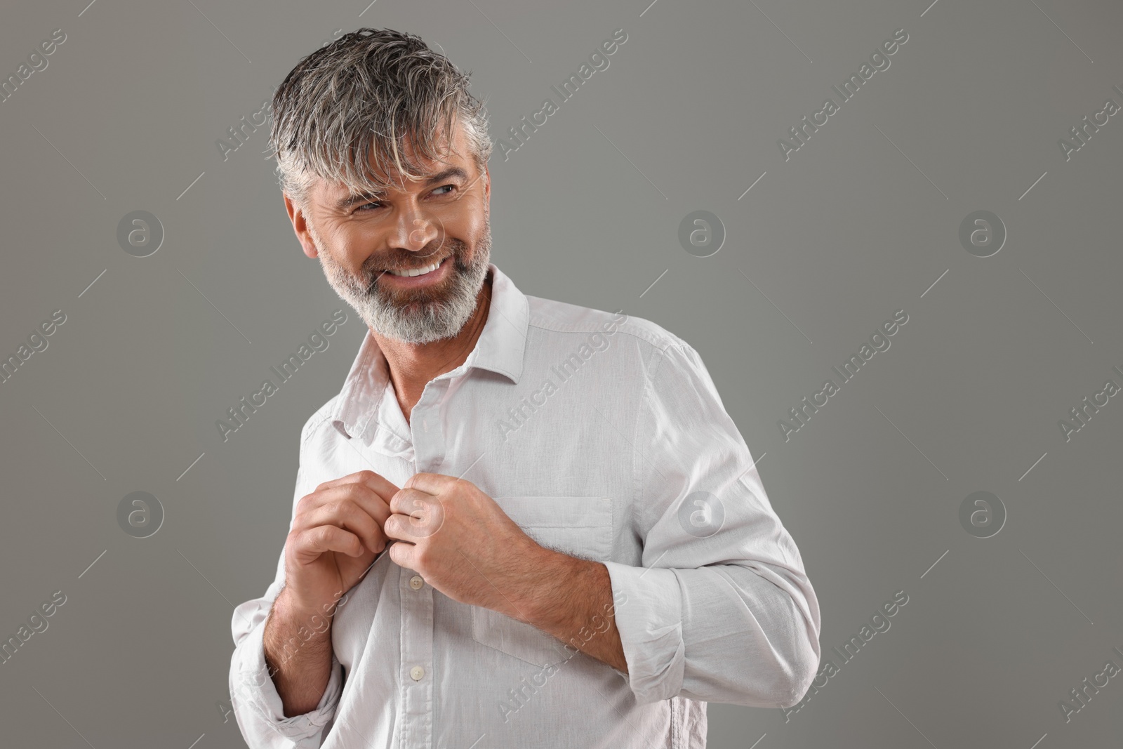 Photo of Portrait of smiling man with beautiful hairstyle on light grey background. Space for text