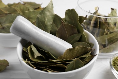 Photo of Bay leaves on white wooden table, closeup view