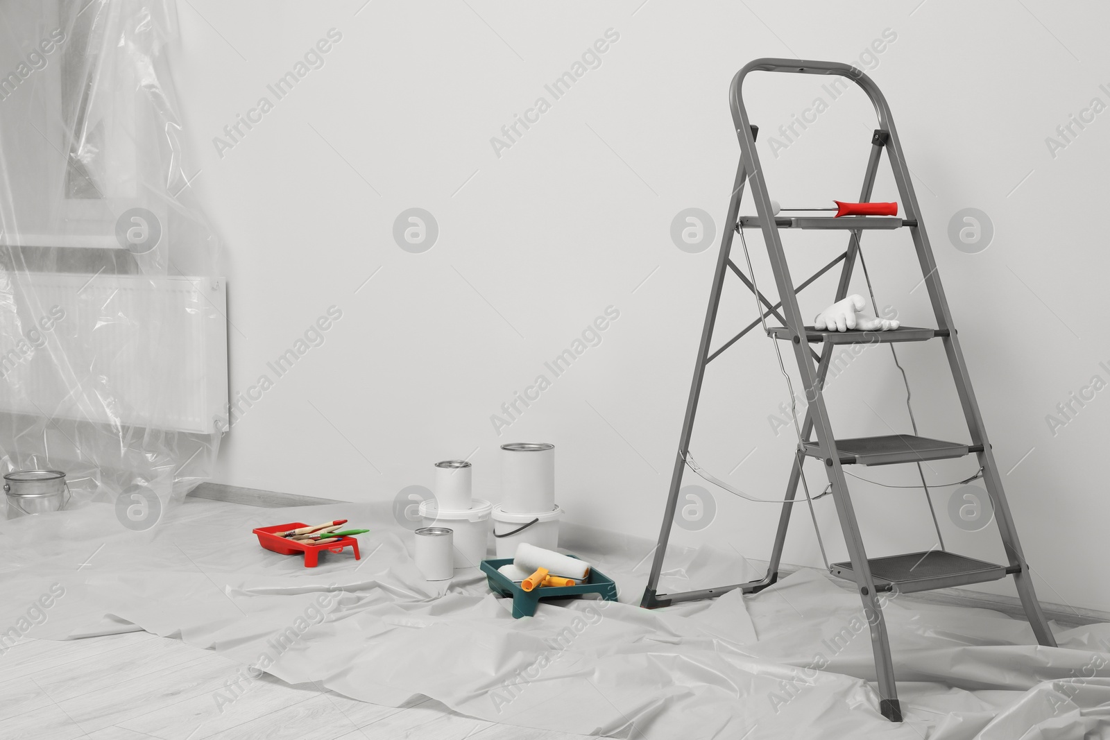 Photo of Metallic folding ladder and painting tools indoors, space for text