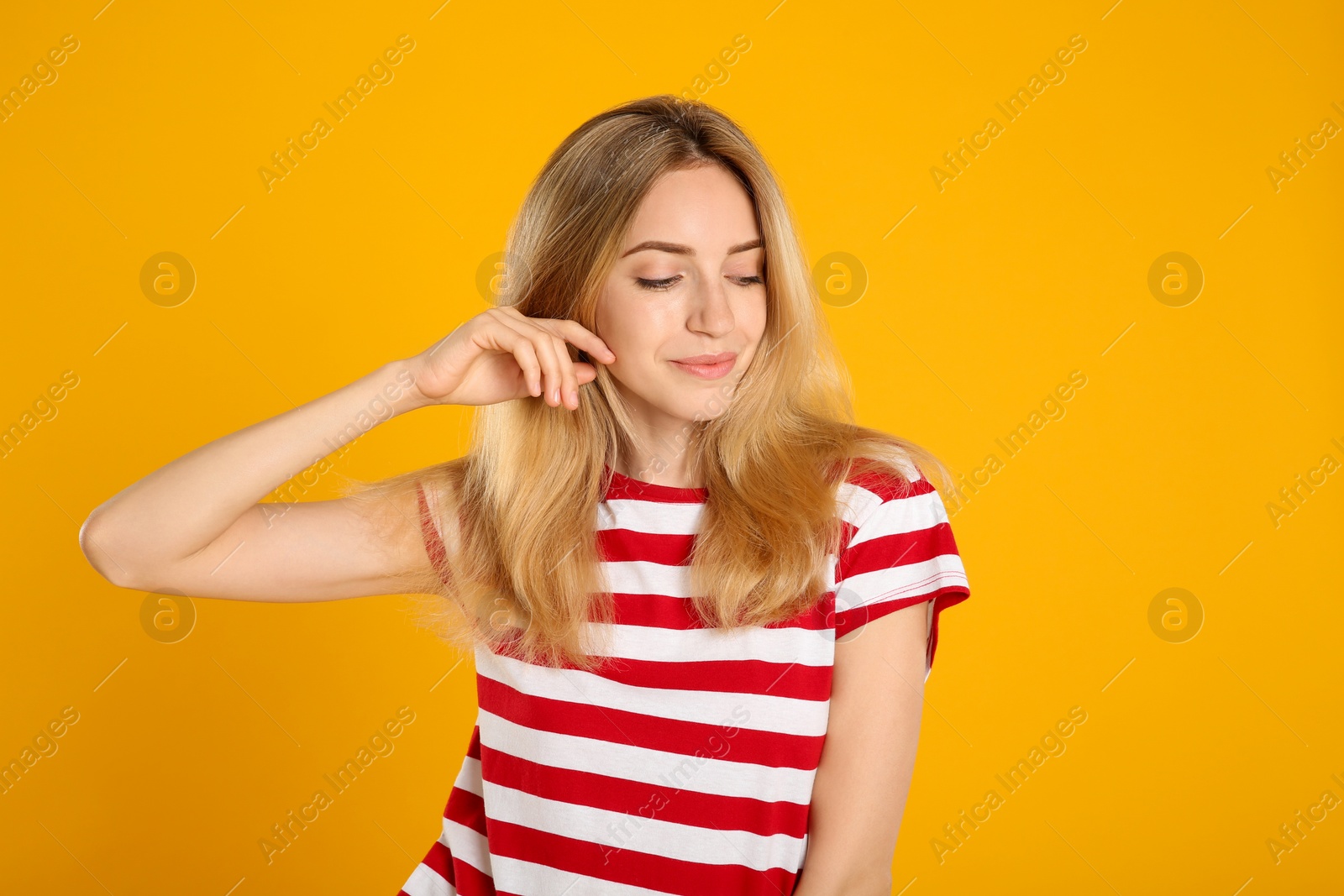 Photo of Portrait of beautiful young woman with blonde hair on yellow background