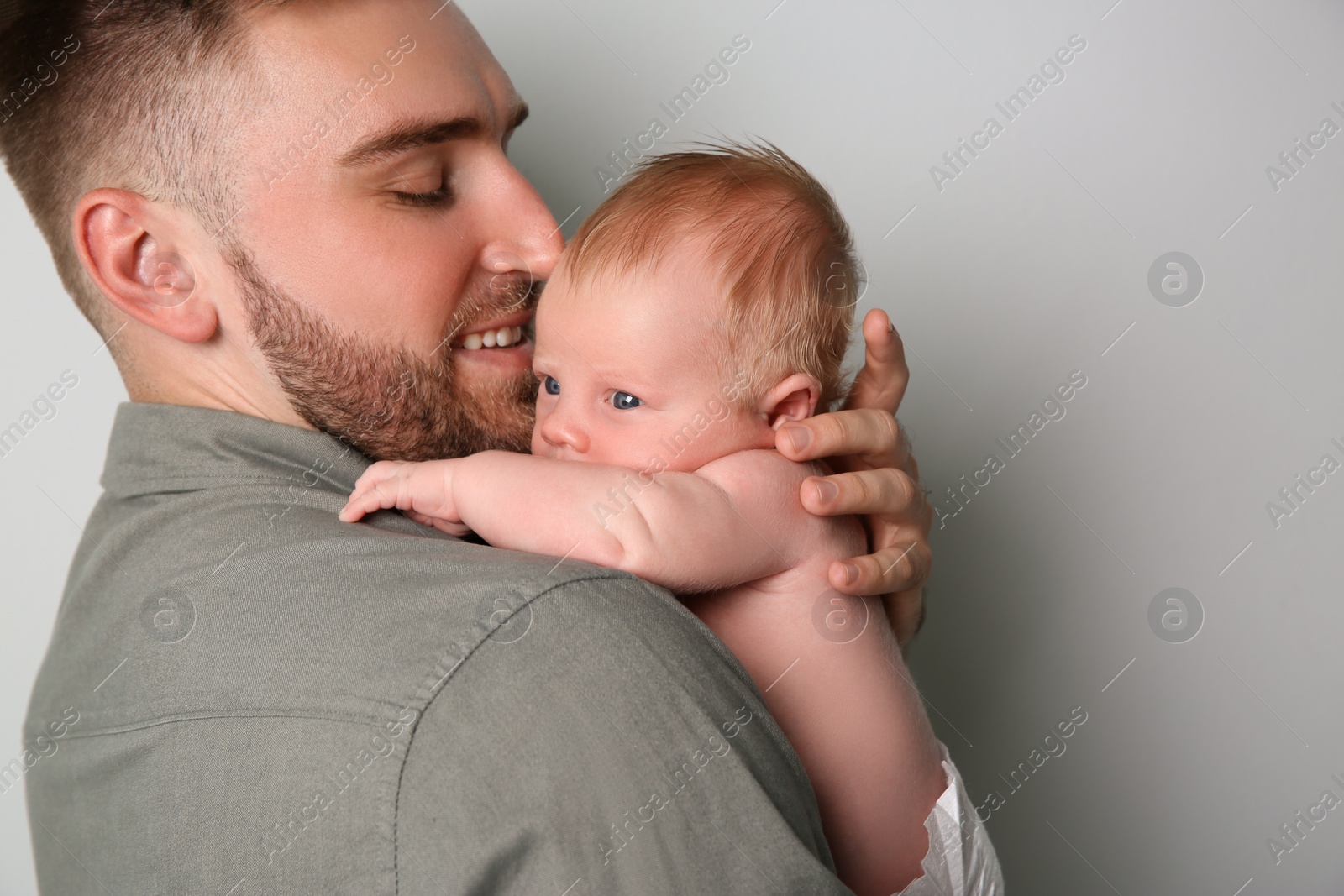Photo of Father with his newborn son on light grey background, closeup