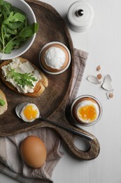 Breakfast with soft boiled eggs served on white wooden table, flat lay