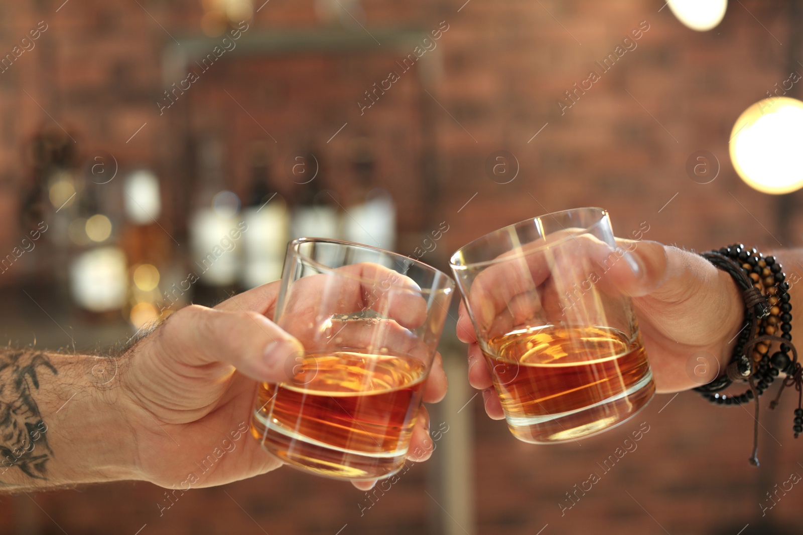 Photo of Friends toasting with glasses of whiskey indoors, closeup