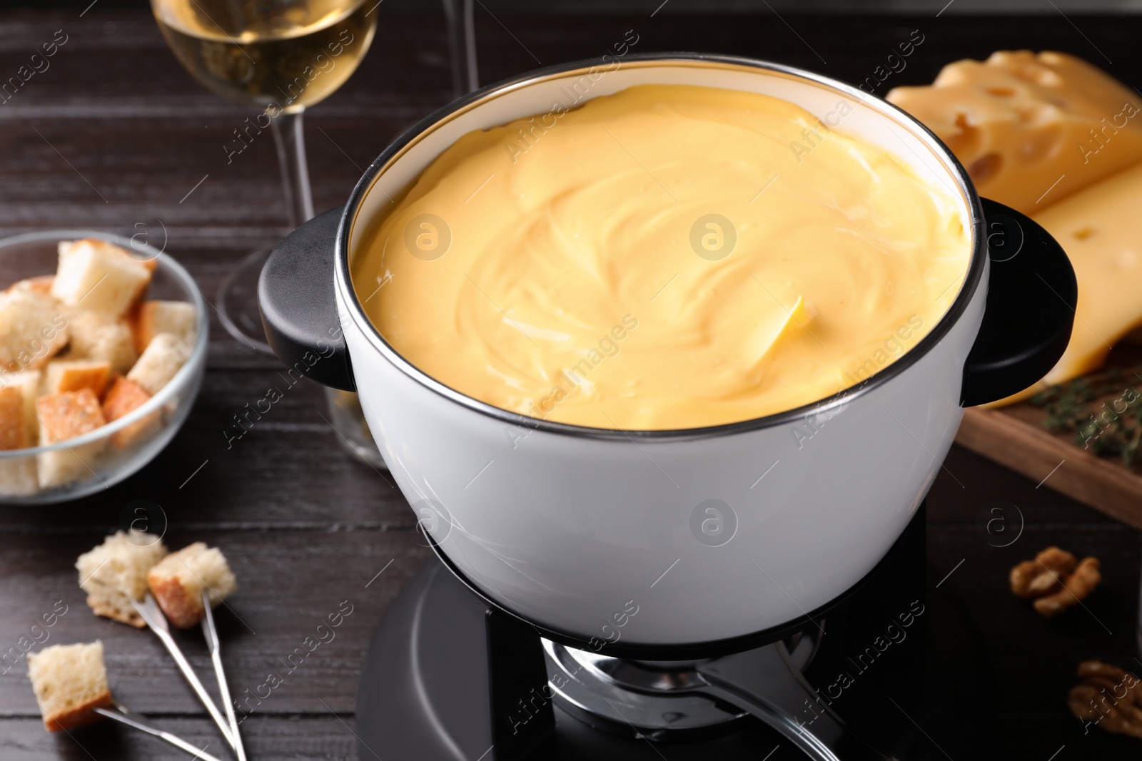 Photo of Pot with delicious cheese fondue on wooden table