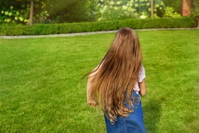 Cute little girl running in green park on summer day