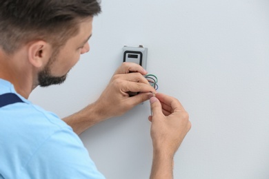 Photo of Young male technician installing alarm system indoors