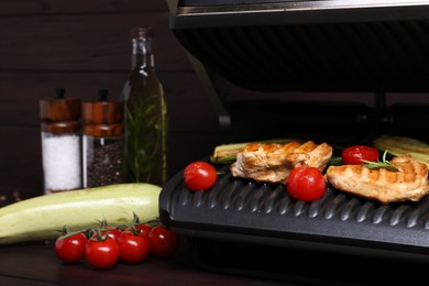 Photo of Electric grill with different products on wooden table