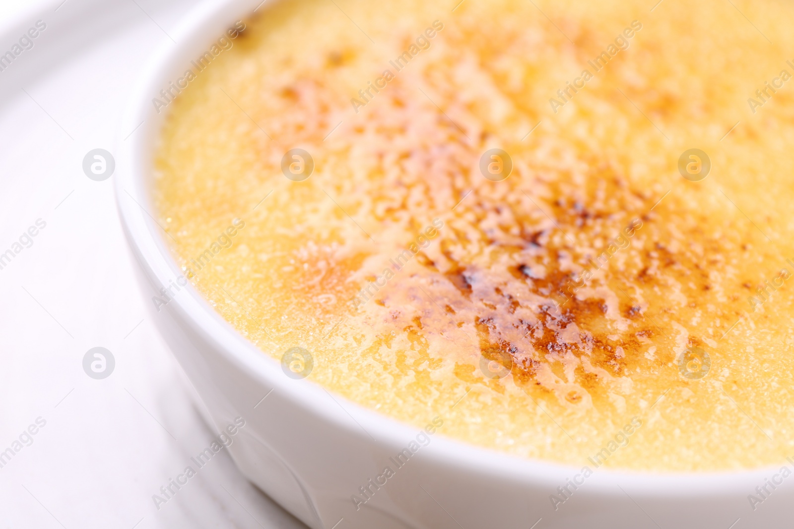 Photo of Delicious creme brulee in bowl on table, closeup