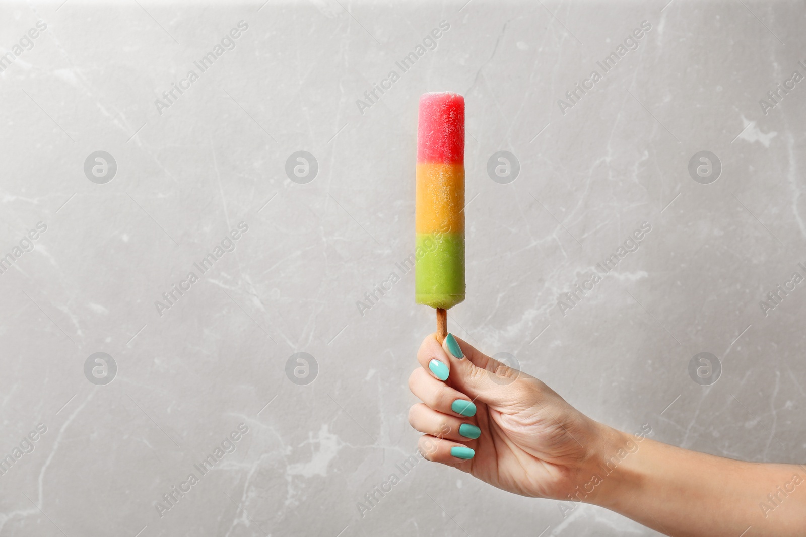 Photo of Woman holding yummy ice cream on light background. Focus on hand