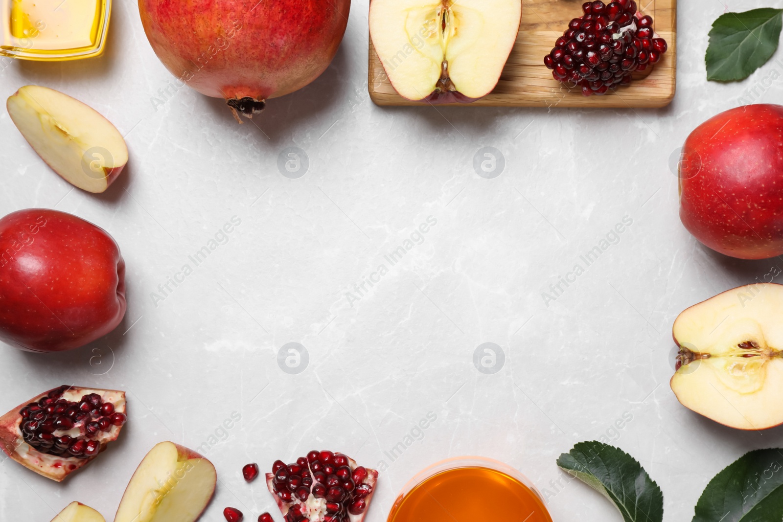 Photo of Frame of honey, apples and pomegranates on white table, flat lay with space for text. Rosh Hashanah holiday