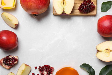 Frame of honey, apples and pomegranates on white table, flat lay with space for text. Rosh Hashanah holiday