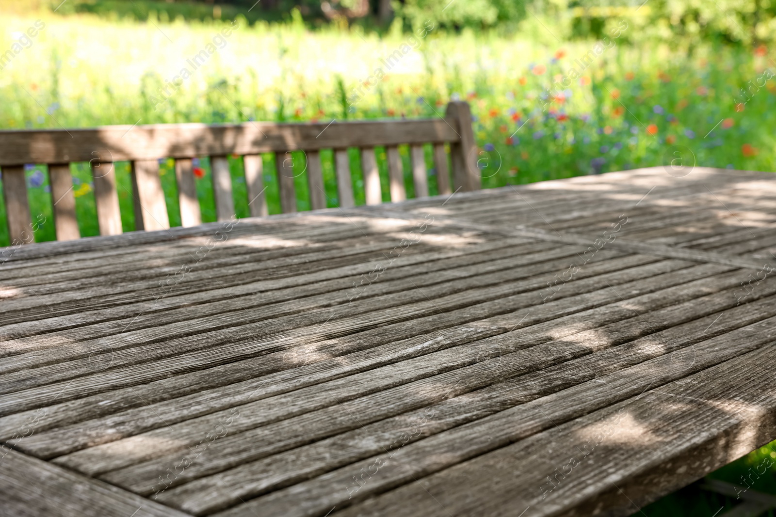 Photo of Empty wooden table with bench on sunny day in garden