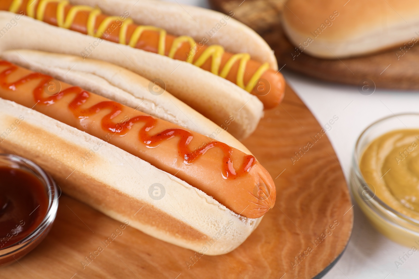 Photo of Tasty hot dogs with ketchup and mustard on white table, closeup