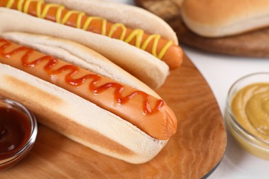 Photo of Tasty hot dogs with ketchup and mustard on white table, closeup