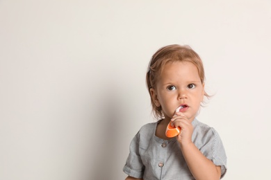 Photo of Cute little girl with toothbrush and space for text on white background