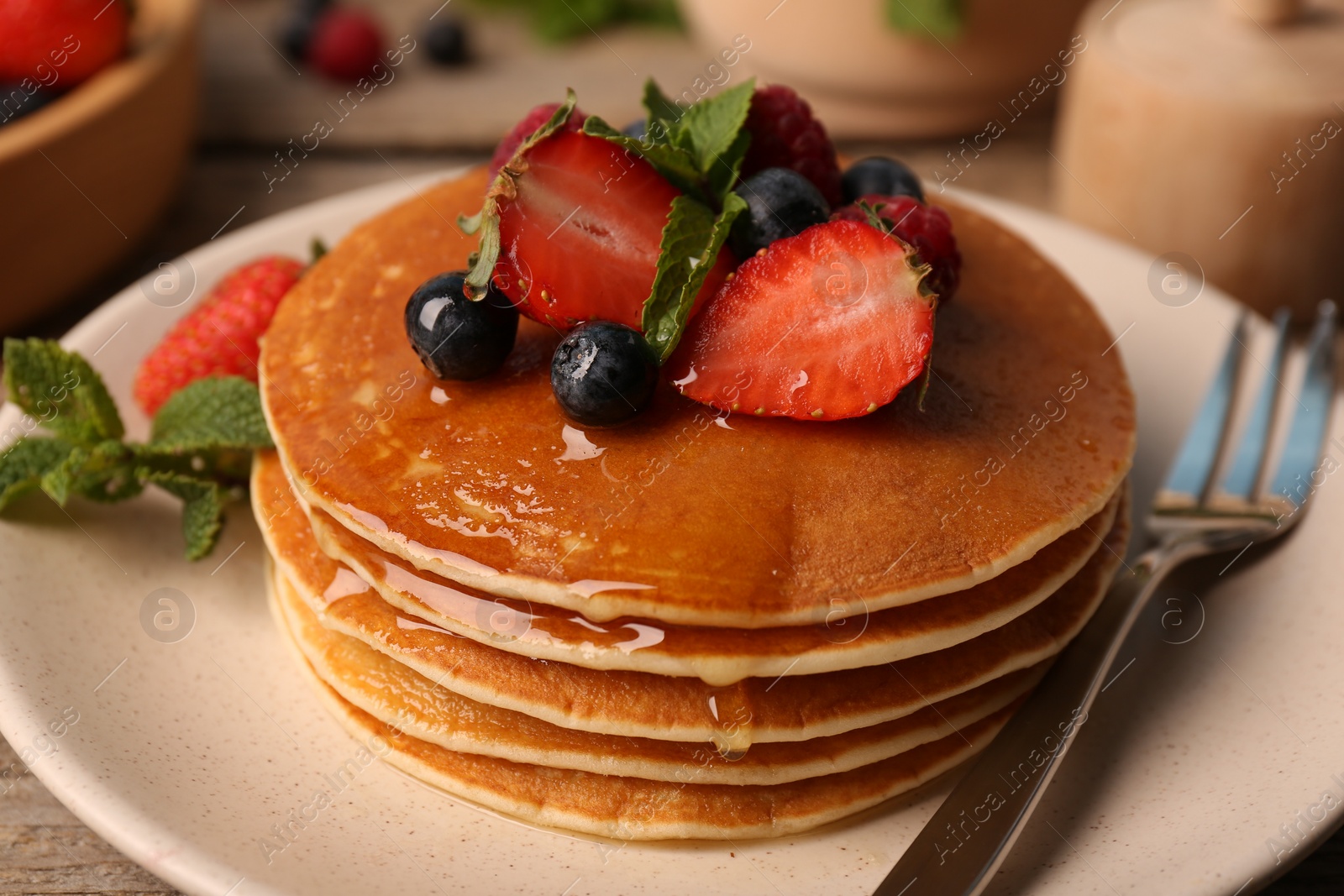 Photo of Tasty pancakes with fresh berries and mint on table, closeup