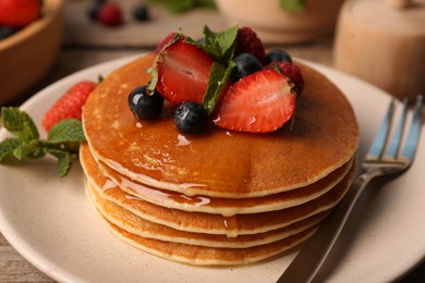 Tasty pancakes with fresh berries and mint on table, closeup