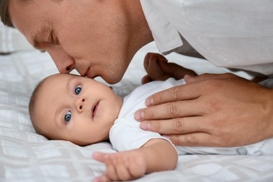 Photo of Father with his cute baby on bed, closeup