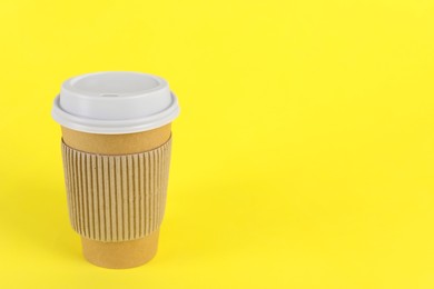 Paper cup with plastic lid on yellow background, space for text. Coffee to go