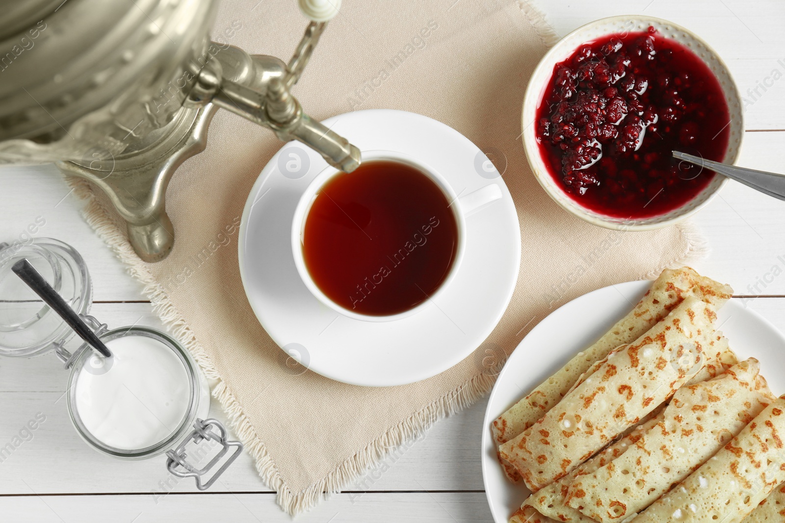 Photo of Vintage samovar, cup of hot drink and snacks served on white wooden table, flat lay. Traditional Russian tea ceremony