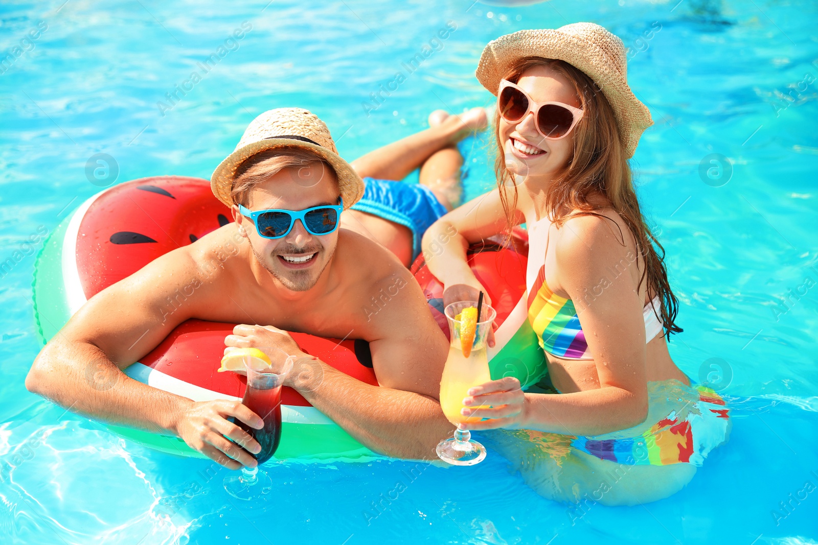 Photo of Young couple with cocktails in pool on sunny day