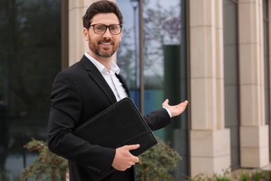 Photo of Real estate agent with leather portfolio outdoors. Space for text