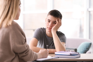 Photo of Young female psychologist working with teenage boy in office