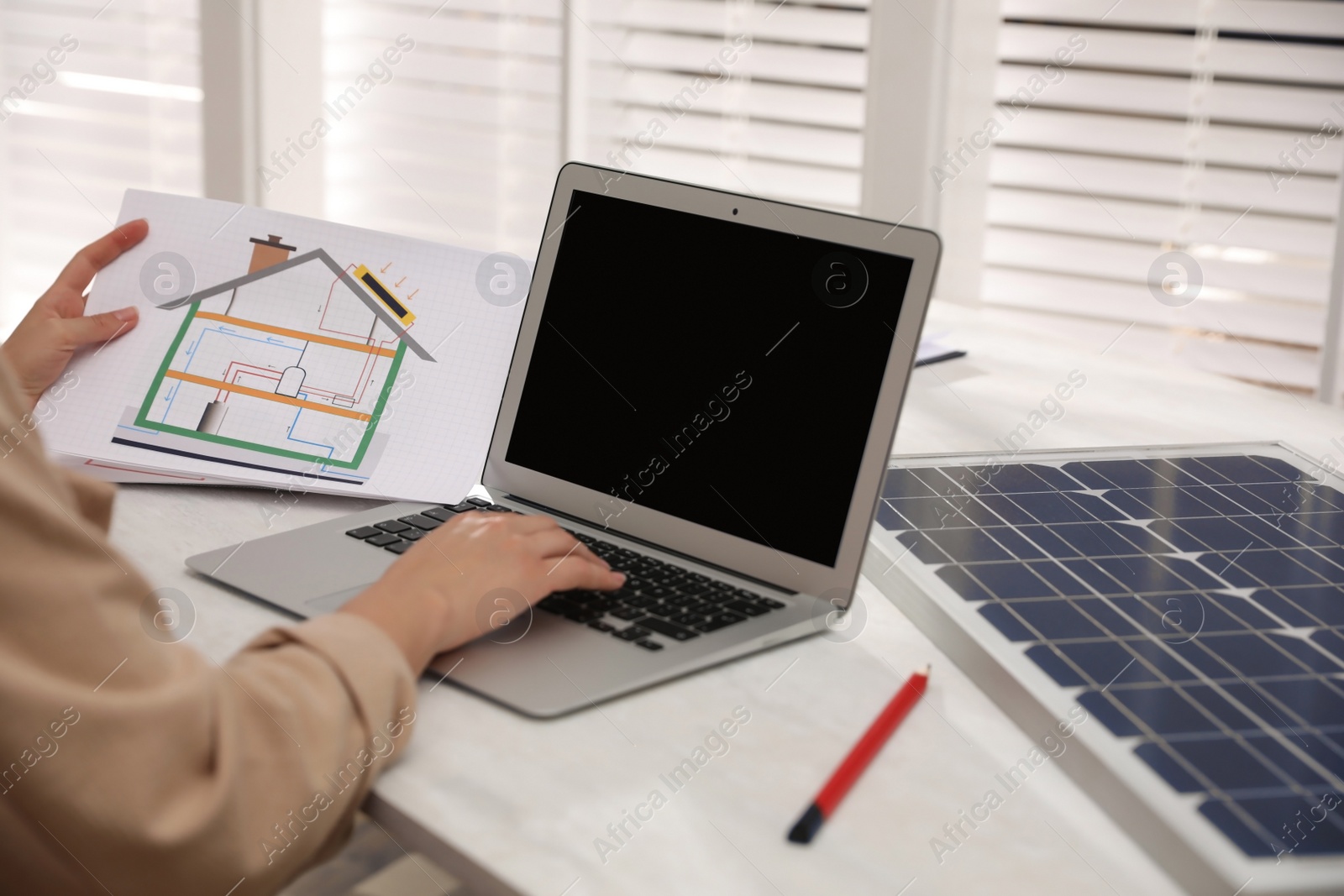 Photo of Woman working on house project with solar panels at table in office, closeup