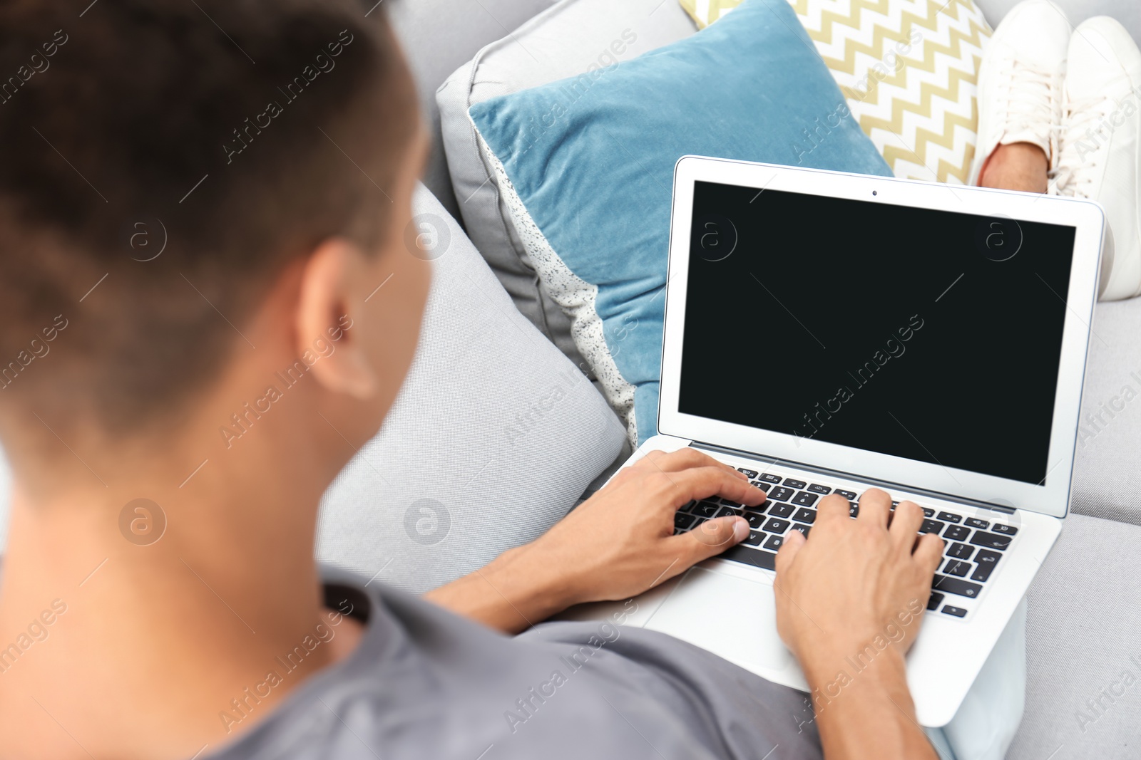 Photo of Man in casual clothes using laptop on sofa at home