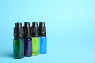 Photo of Bottles with different food coloring on light blue background, space for text