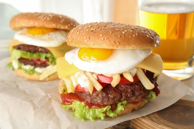 Photo of Tasty burgers with fried egg on wooden board