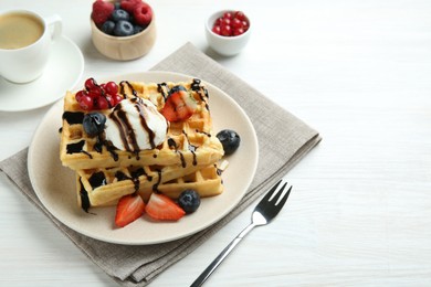 Photo of Delicious Belgian waffles with ice cream, berries and chocolate sauce served on white wooden table. Space for text