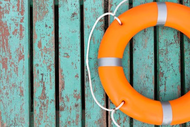 Photo of Orange life buoy on turquoise wooden background, top view. Space for text