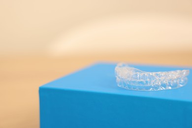 Photo of Transparent dental aligners on beige background, closeup. Space for text