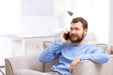 Photo of Portrait of confident mature man with mobile phone in armchair