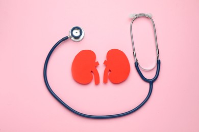 Paper cutout of kidneys and stethoscope on pink background, flat lay