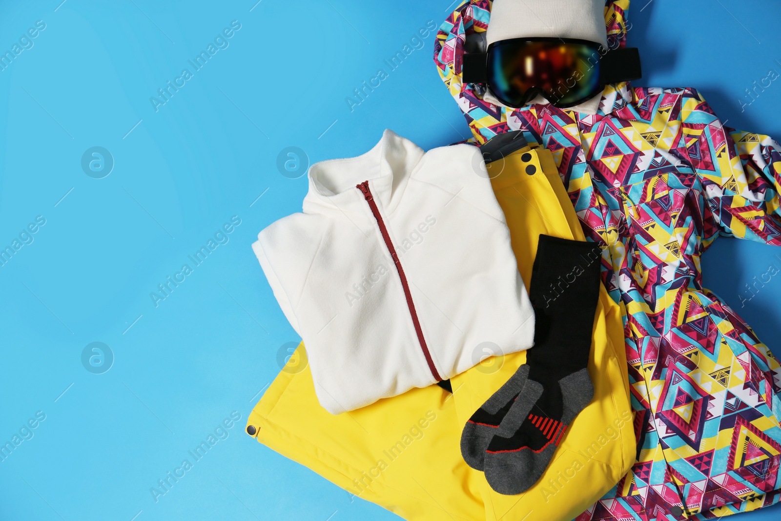 Photo of Stylish winter sport clothes on light blue background, flat lay. Space for text