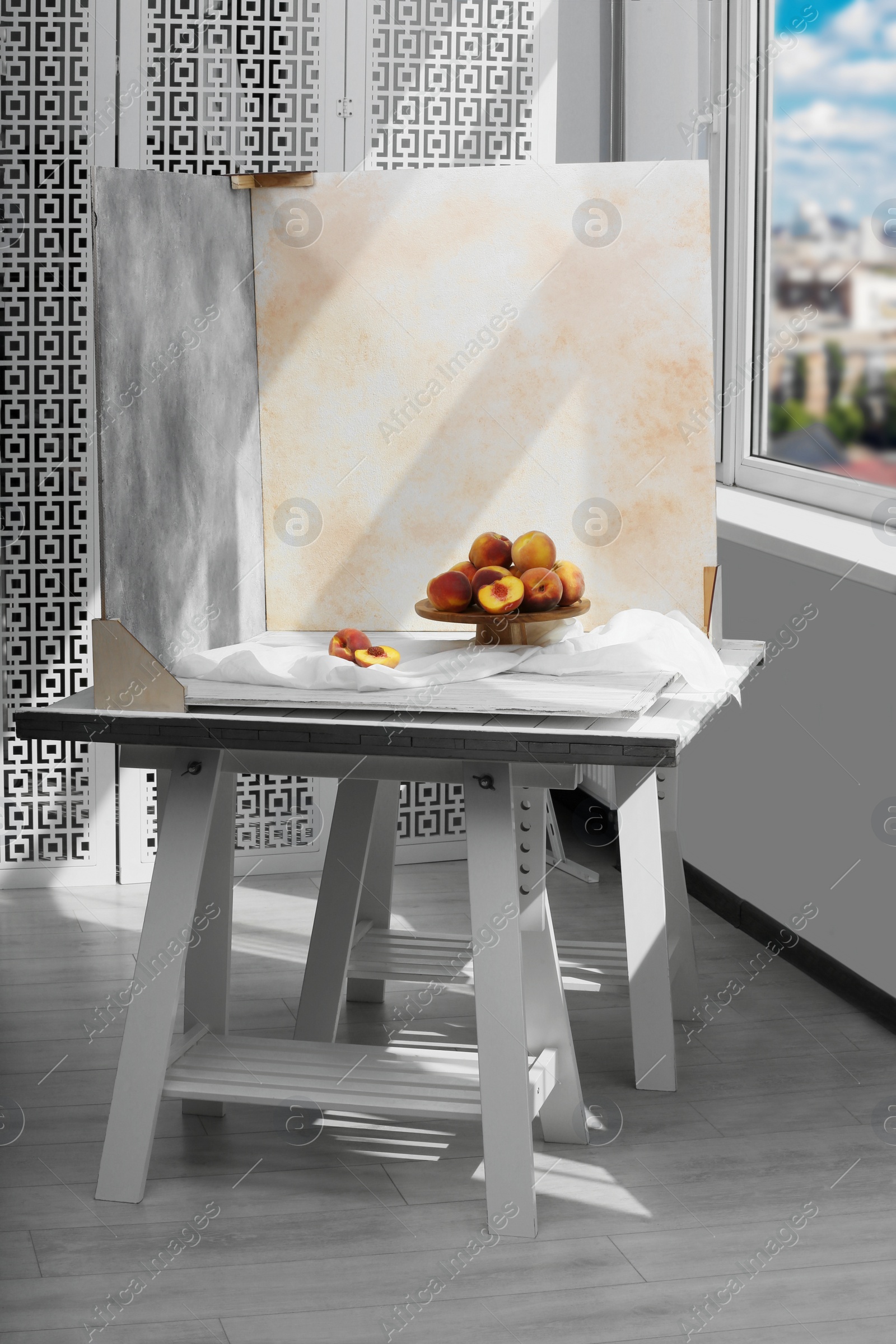 Photo of Stand with juicy peaches and double-sided backdrops in photo studio