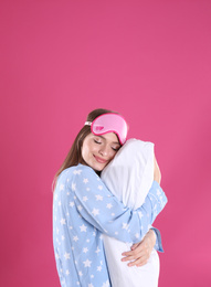 Photo of Young woman with pillow and sleep mask on pink background