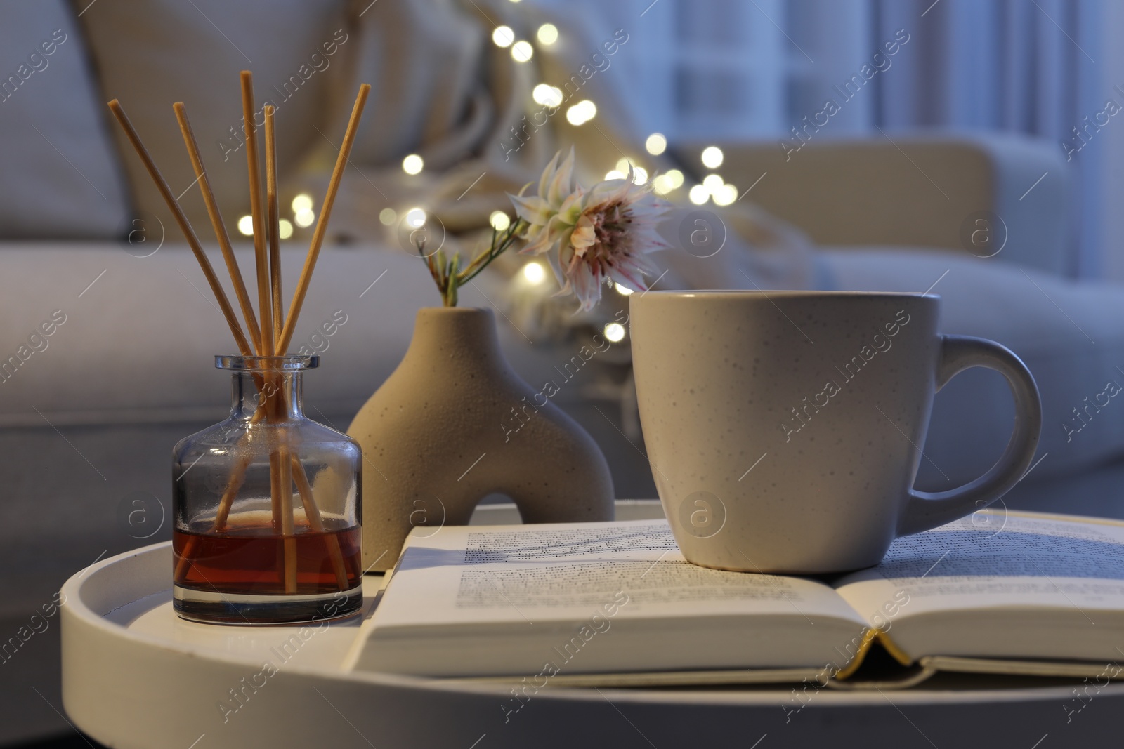 Photo of Cup of drink, air freshener and book on table indoors