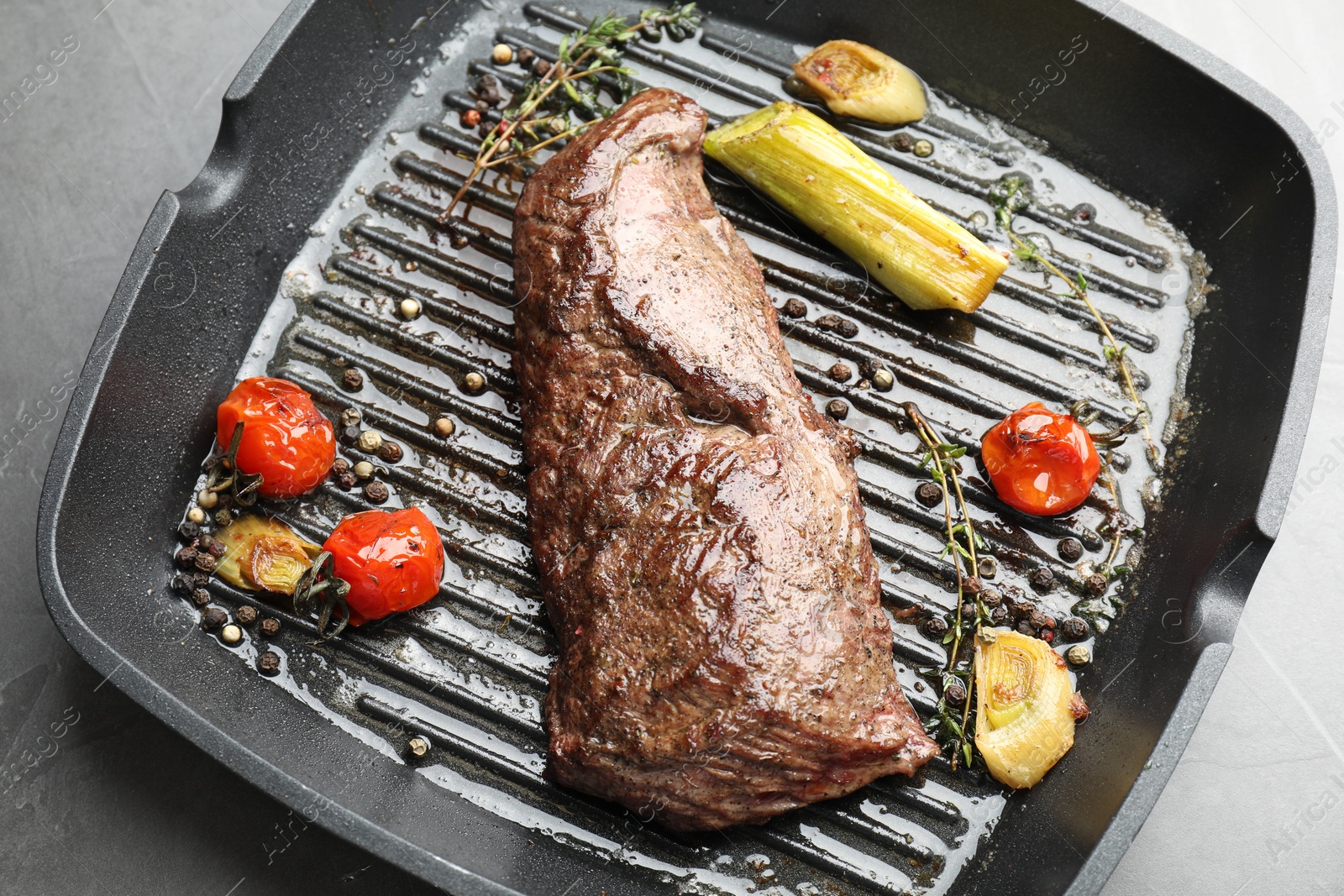 Photo of Delicious grilled beef meat and vegetables in pan on grey table, top view