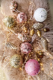 Photo of Beautiful Christmas tree baubles and fairy lights on faux fur, flat lay