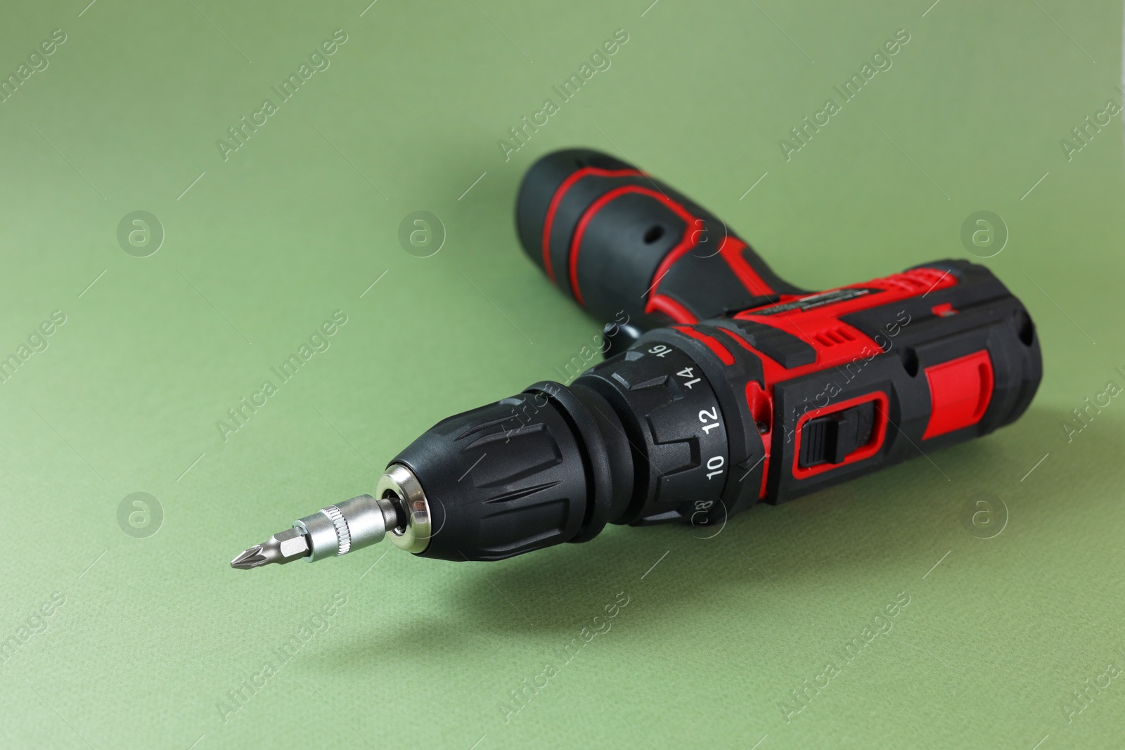 Photo of Modern electric screwdriver on pale green background