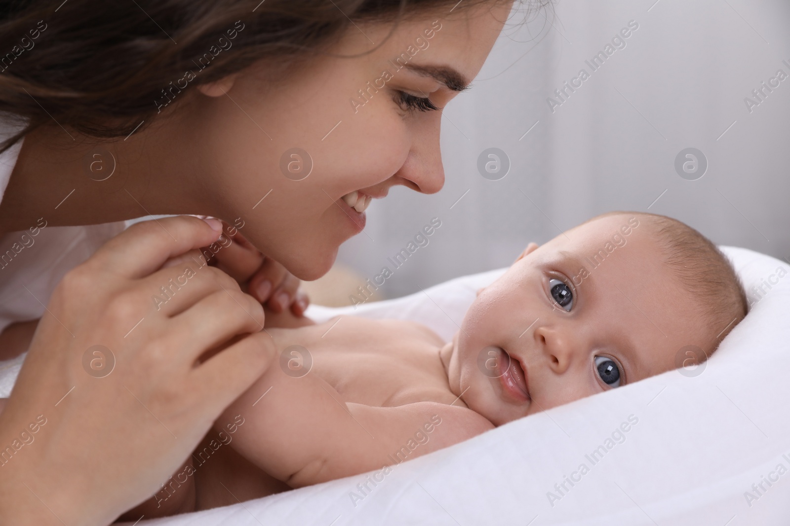 Photo of Happy young mother with her cute baby on bed at home, closeup