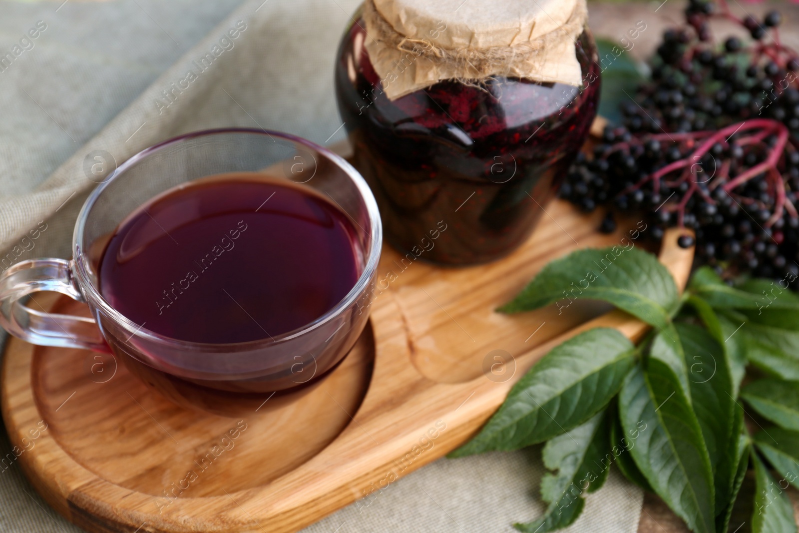 Photo of Elderberry jam, glass cup of tea and Sambucus berries on table