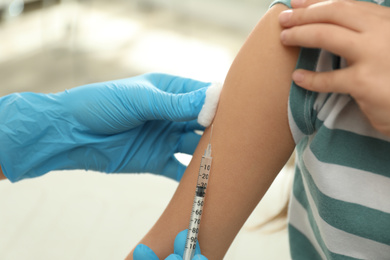 Doctor vaccinating little child in clinic, closeup