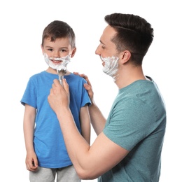 Photo of Dad applying shaving foam onto son's face against white background