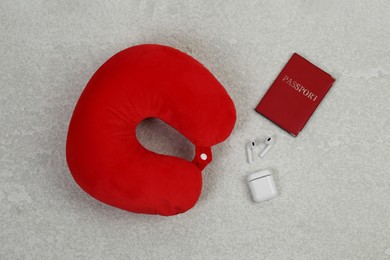 Photo of Soft travel pillow, passport and earphones on grey textured background, flat lay