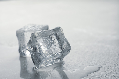 Photo of Crystal clear ice cubes with water drops on grey table, closeup. Space for text