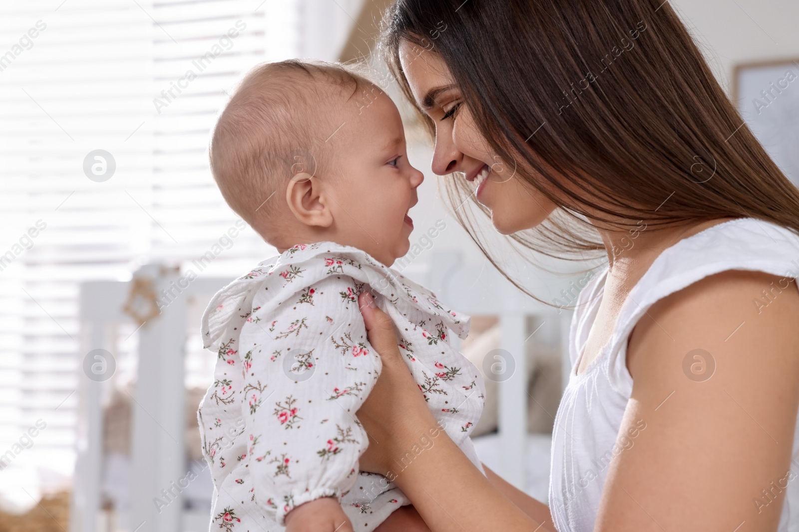 Photo of Happy young mother with her baby daughter in nursery